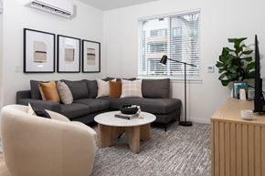 University Place apartment for rent - A living room with a grey couch, a white chair, a wooden coffee table, and a TV on a wooden stand.