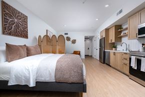 Montclair apartment for rent - A bedroom with a large bed and a kitchen area in the background.