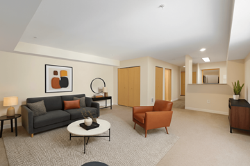 Bellevue apartment for rent - A living room with a grey couch, a white coffee table, a round mirror, a lamp, a plant, and a painting on the wall.