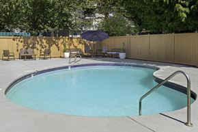 Everett apartment for rent - Fenced pool area with patio seating and an umbrella at Casa Blanca Apartment Homes, Everett, WA, 98204