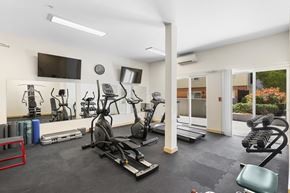 Seattle apartment for rent - a gym with cardio equipment and a flat screen tv at Guinevere Apartment Homes, Washington