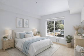 Seattle apartment for rent - A bedroom with a large bed, a nightstand, a dresser, and a window with a view of trees and buildings outside.