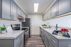Seattle apartment for rent - A kitchen with grey cabinets and a white countertop. at Hill Crest Apartment Homes, Seattle, 98126