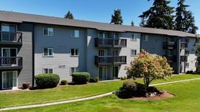 Edmonds apartment for rent - A tree with red flowers is in the front yard of a grey apartment building.