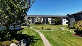Edmonds apartment for rent - A grassy area with benches and a walking path in front of apartment buildings.