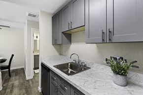 Lynnwood apartment for rent - a kitchen with gray cabinets and a stainless steel sink at Pinewood Square Apartment Homes, Washington