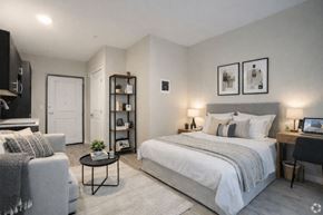 Seattle apartment for rent - A well-lit bedroom with a large bed, a grey sofa, and a desk with a laptop.