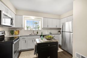 Rochester Hills apartment for rent - a kitchen with white cabinets and a black island with a bottle of wine on it  at Northridge, Rochester Hills, Michigan