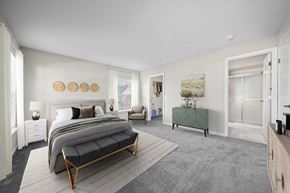 Canton apartment for rent - A bedroom with a large bed and a green bench.