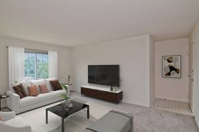 Herndon apartment for rent - A living room with a white couch, a black television, and a coffee table at Dulles Glen, Herndon