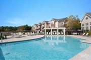 Spring Lake apartment for rent - A large swimming pool in front of a building with a white pergola. at Village on the Lake Apartments, North Carolina