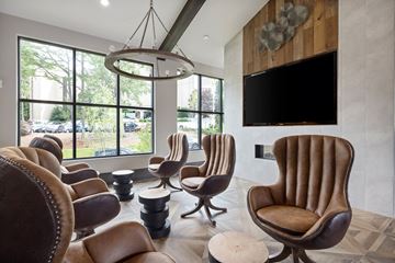 Raleigh apartment for rent - A living room with brown leather chairs and a flat screen TV mounted on the wall.