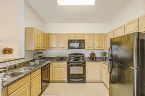 Spring Lake apartment for rent - a kitchen with wood cabinets and black appliances  at Stone Gate Apartments, Spring Lake, North Carolina