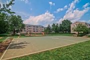 Herndon apartment for rent - A basketball court is surrounded by grass and trees in front of a building at Dulles Glen Apartments, Herndon, Virginia