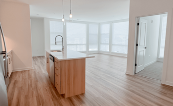 An empty kitchen and living room with white blinds on the window