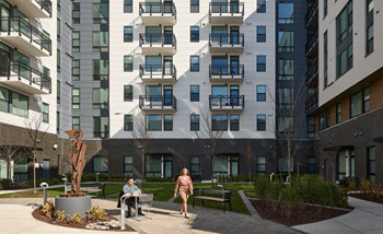 People walking in a park in front of an apartment building
