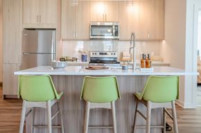 Herndon apartment for rent - a kitchen with green chairs in front of a counter top at Makers Rise, Herndon, VA 20171