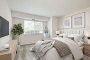 Fairfax apartment for rent - A bedroom with a large bed, a desk with a keyboard, and a plant at Fairfax Square Apartments, Fairfax, VA, 22031