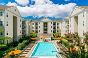 Woodbridge apartment for rent - A large swimming pool surrounded by lounge chairs and umbrellas in front of apartment buildings. at Kensington Place Apartments, Virginia