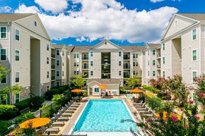 Woodbridge apartment for rent - A large swimming pool surrounded by lounge chairs and umbrellas in front of apartment buildings. at Kensington Place Apartments, Virginia