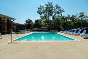 Mundelein apartment for rent - A large swimming pool surrounded by chairs and trees.