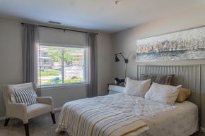 Mundelein apartment for rent - A bedroom with a large bed and a chair by the window.