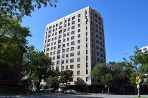 Chicago apartment for rent - A tall building with many windows is surrounded by trees.