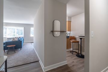 Glen Ellyn apartment for rent - A living room with a blue couch and a dining area with a table and chairs.