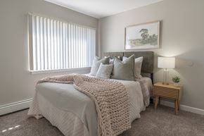Glen Ellyn apartment for rent - A bedroom with a large bed covered in a white blanket and pillows.