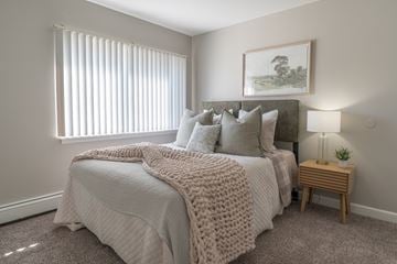 Glen Ellyn apartment for rent - A bedroom with a large bed covered in a white blanket and pillows.