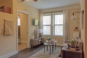 Chicago apartment for rent - A living room with a brown couch, a coffee table, and a window with white curtains.