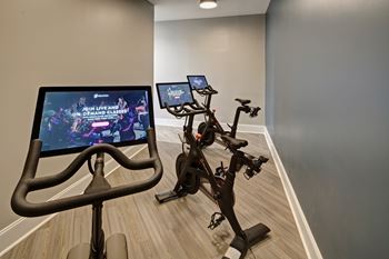 Home fitness room with stationary bikes and screens