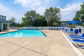 Schaumburg apartment for rent - A large outdoor swimming pool surrounded by blue lounge chairs.