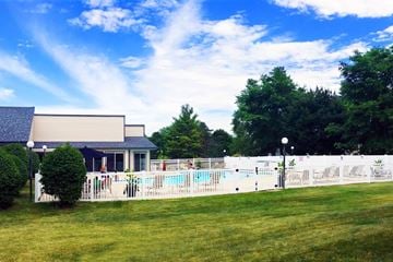 Schaumburg apartment for rent - A pool surrounded by a white fence and a building in the background.