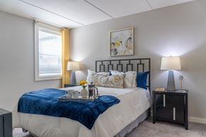 Schaumburg apartment for rent - A bedroom with a bed, nightstand, and a painting on the wall.
