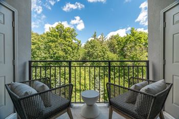 Balcony seating area with treetop views and black railing