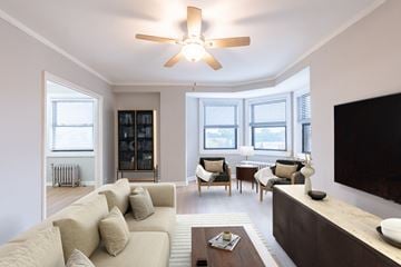 Chicago apartment for rent - A living room with a beige couch and a ceiling fan.