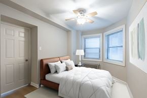 Chicago apartment for rent - A bedroom with a bed, pillows, a ceiling fan, and a window with blinds.