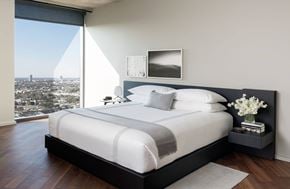 West Hollywood apartment for rent - A bedroom with a large bed and a city view through the window.