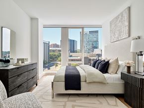 White Plains apartment for rent - A modern bedroom with a large bed and a view of the city.