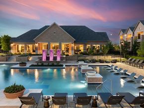 Irving apartment for rent - a large swimming pool with lounge chairs and a house in the background at AVE Las Colinas, Irving, TX