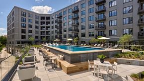 Philadelphia apartment for rent - A pool surrounded by chairs and tables is in front of a building.