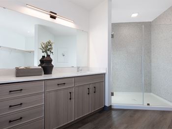 Bathrooms feature oversized walk-in showers with glass doors and/or garden-style soaking tubs, natural earth-inspired tile, deep sinks, and soft-close cabinetry