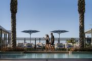 Phoenix apartment for rent - a man and woman standing next to a pool at a hotel with umbrellas at AVE Phoenix Terra, Arizona, 85003