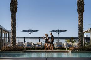 Phoenix apartment for rent - a man and woman standing next to a pool at a hotel with umbrellas at AVE Phoenix Terra, Arizona, 85003