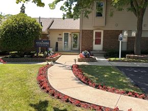 Grand Blanc townhouse for rent - a sidewalk in front of a building with flowers and plants