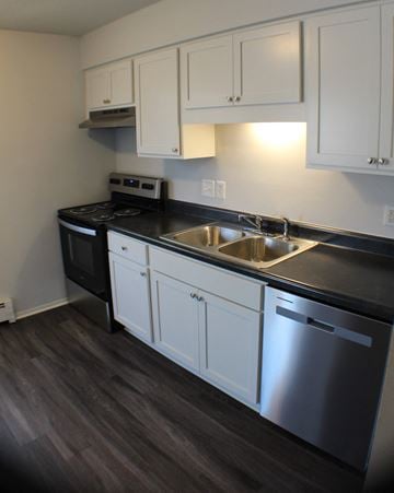 Durand apartment for rent - a kitchen with white cabinets and black countertops and a stainless steel sink