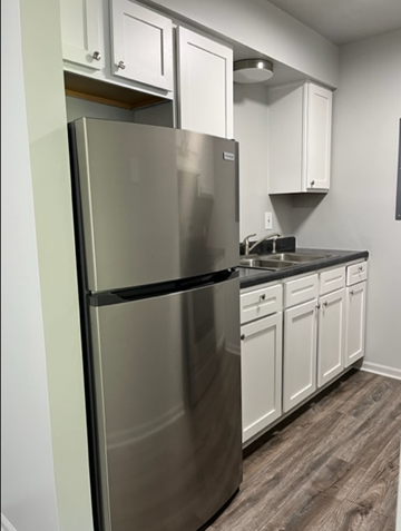 Clio apartment for rent - a kitchen with white cabinets and a stainless steel refrigerator