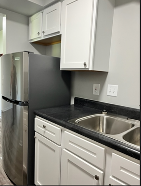 Clio apartment for rent - a kitchen with white cabinets and a stainless steel refrigerator