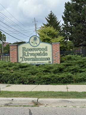 Flint townhouse for rent - A sign for Rosewood Riverside Townhomes is displayed in front of a fence.